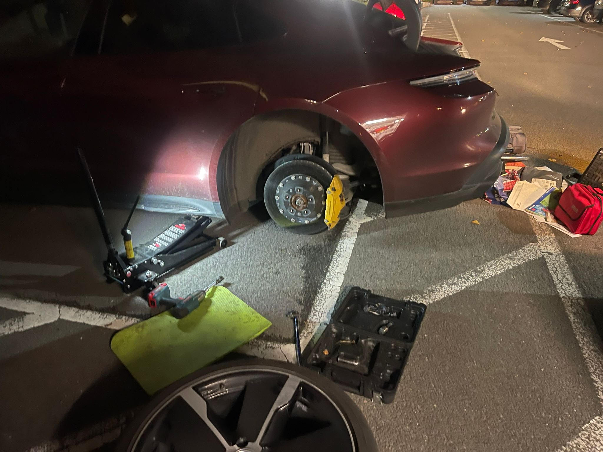 Porsche with wheel removed during emergency mobile tyre fitting at night